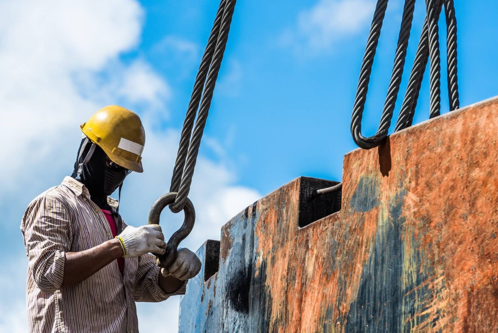 A worker in a hard hat is engaged in tasks on a ship, demonstrating safety and diligence in a maritime environment
