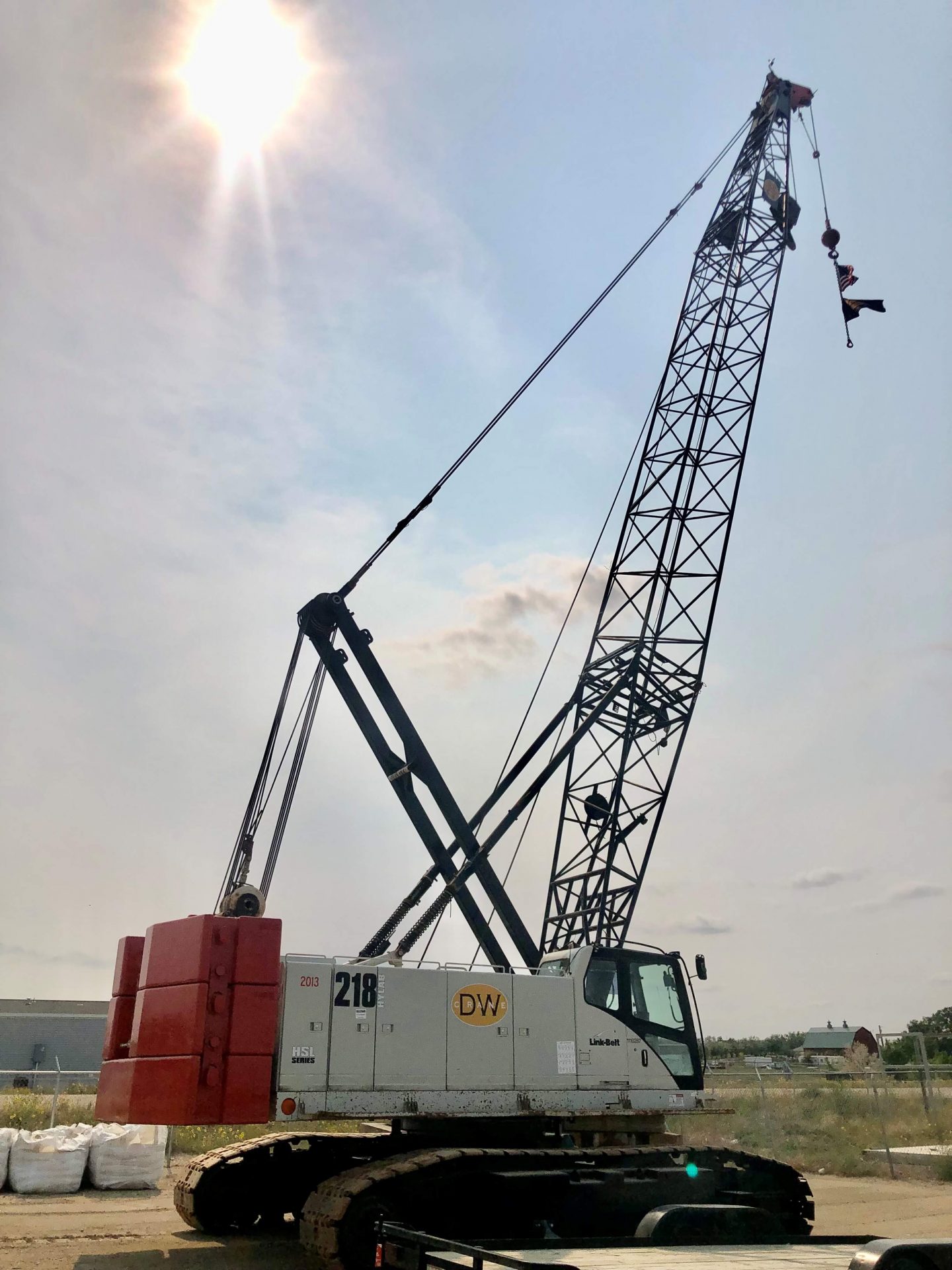 A crane lifts a large object on a dirt lot, showcasing construction activity in progress.
