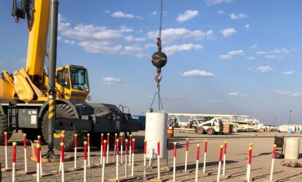 A crane lifts a large object above a field, showcasing construction or heavy lifting in progress.