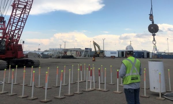 A man stands beside a crane, with another crane visible in the background.